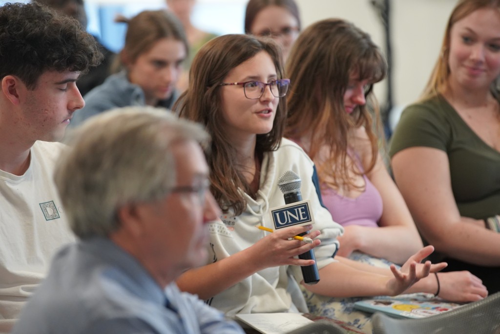 A student holding a microphone asks a question during a CECE event