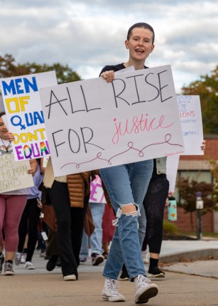 A student holds a sign that reads "All rise for justice" during a Women's March