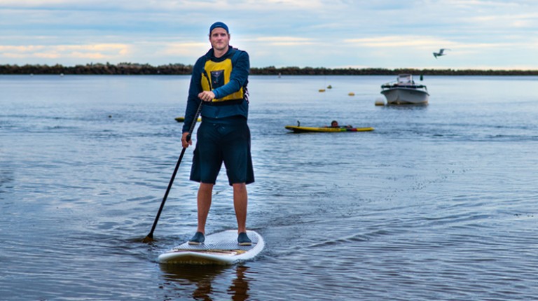 A student coming back to shore after paddle boarding