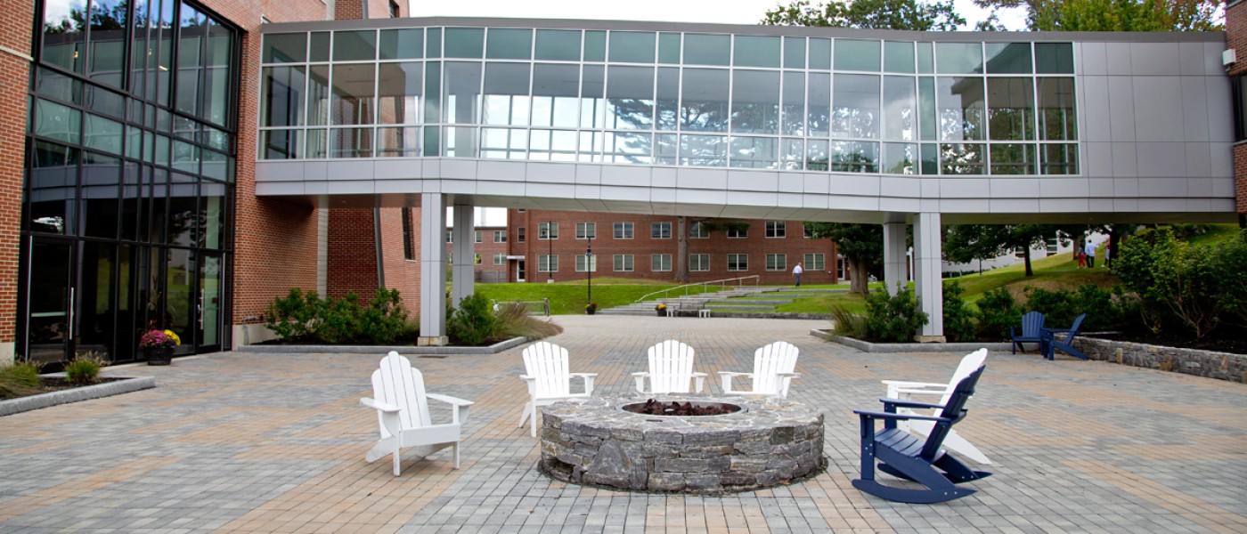 Several Adirondack chairs around a fire pit outside the Commons
