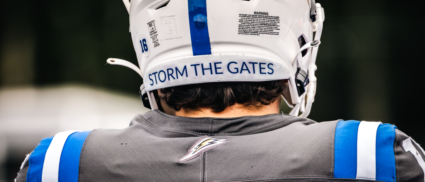 A football player's helmet reads "Storm the Gates"