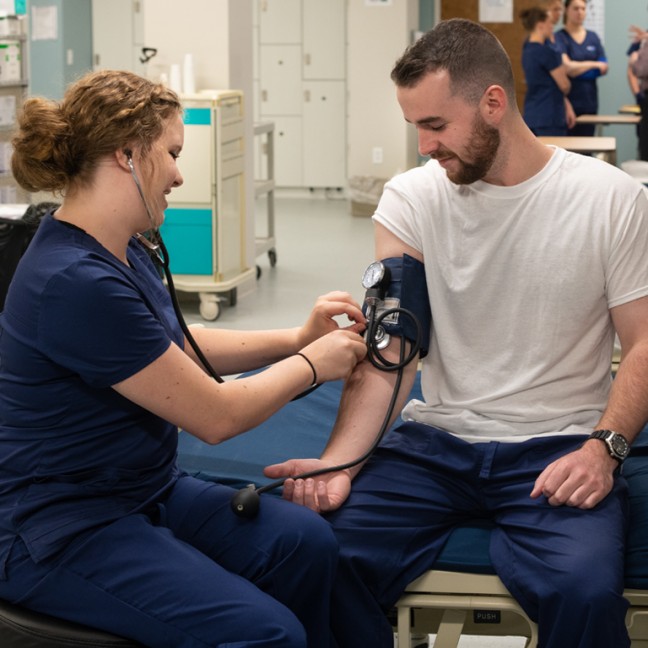 a female student takes the blood pressure of a male student